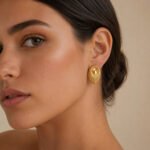 siknakit-soleil-pleat-zlati-vticni-uhani-s-pahljacastim-reliefom-closeup-na-usesu