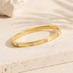 sik-nakit-zlata-bangle-zapestnica-s-cirkoni-lumiere-dot-bangle-kamnito-ozadje