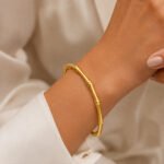 siknakit-zlata-odprta-zapestnica-z-bambusovo-strukturo-bamboo-grace-cuff-closeup-na-zapestju
