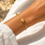siknakit-zlata-zapestnica-shell-open-bangle-close-up-na-roki-bela-tkanina