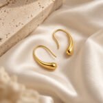 sik-nakit-contour-drop-gold-zlati-viseci-uhani-z-mehko-zaobljeno-obliko-saten-travertin-podlaga