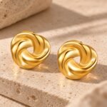 sik-nakit-sculpted-swirl-gold-zlati-skulpturalni-vticni-uhani-travertin-podlaga